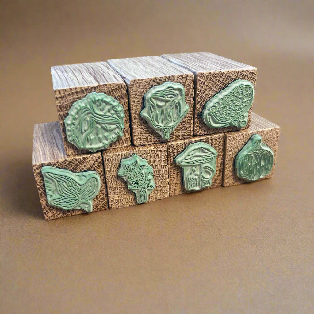 Close up of a stack of wooden botanical rubber stamps, 3 stamps sit on 4 stamps. The laser cut rubber is green