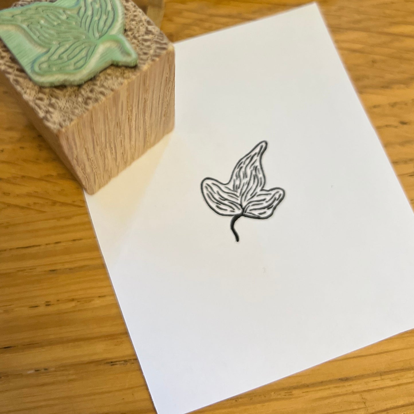 Close up of an ivy leaf stamped in black on a square of white paper