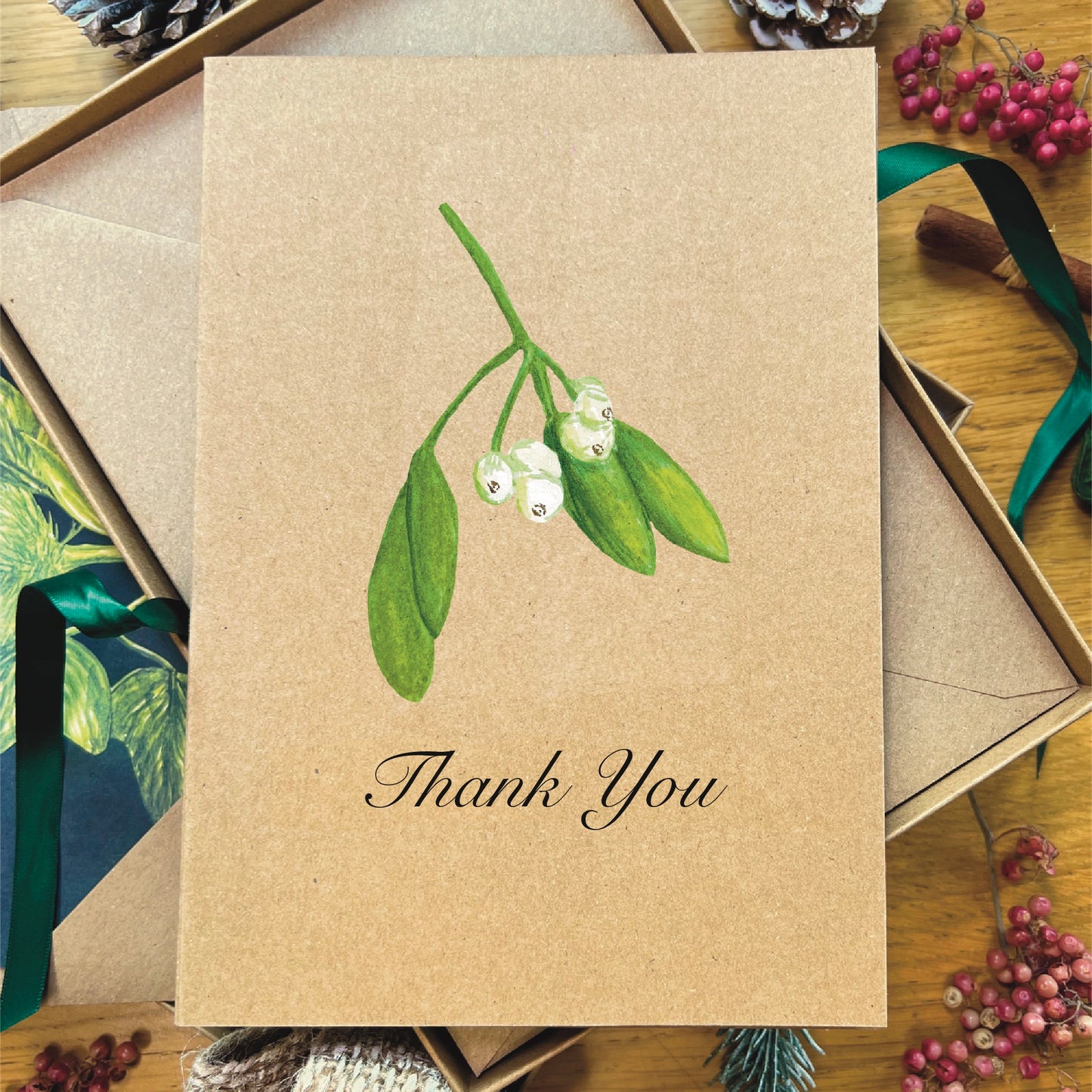 Mistletoe painted in watercolour attached to a natural recycled blank greetings card, laying in a box with an illustrated inlay envelope