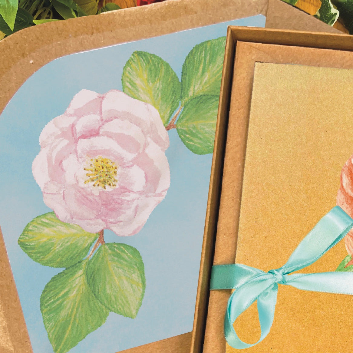 Brown envelope close up with sky blue inlay decorated with a beautiful blush pink rose