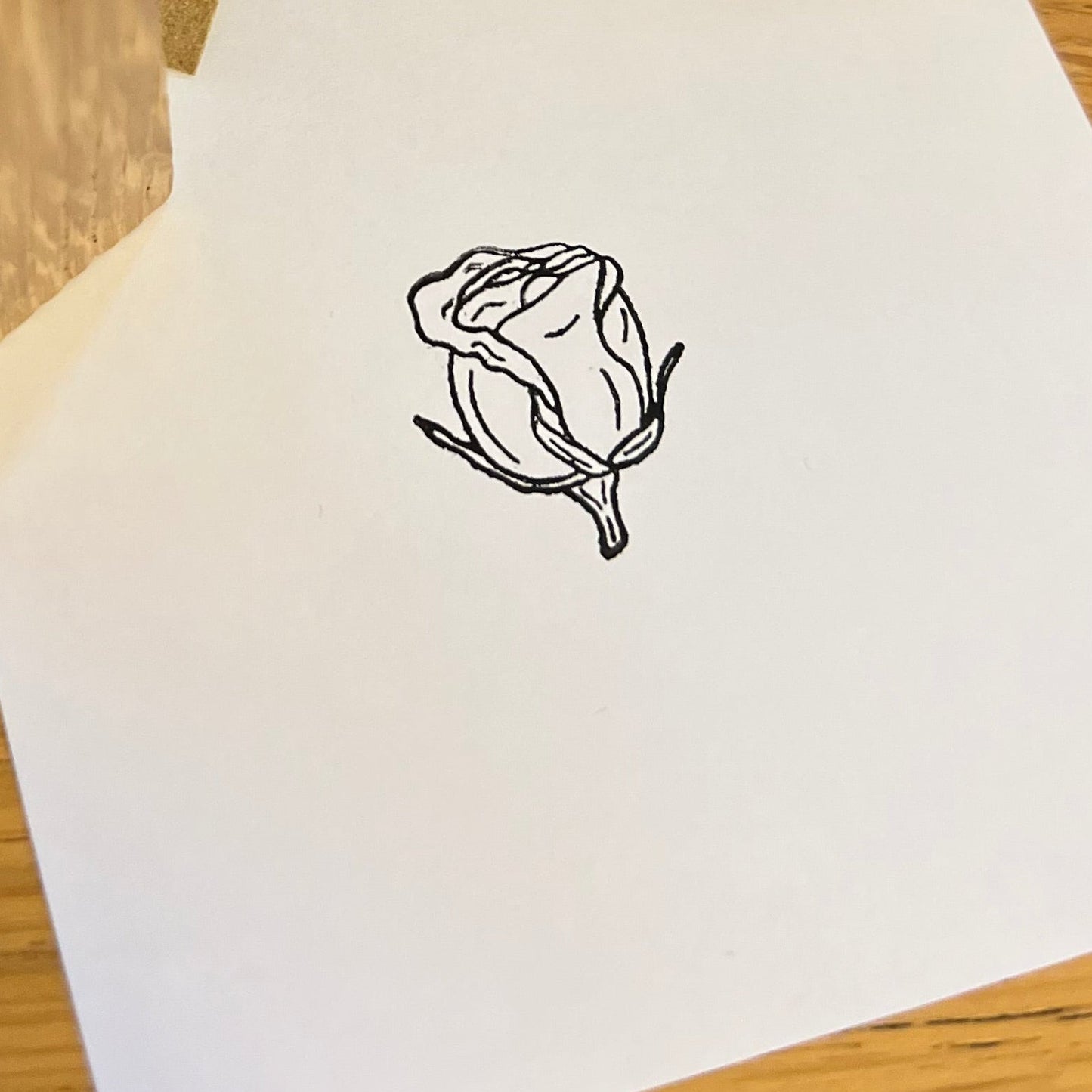 Black ink stamped rose bud on a white paper