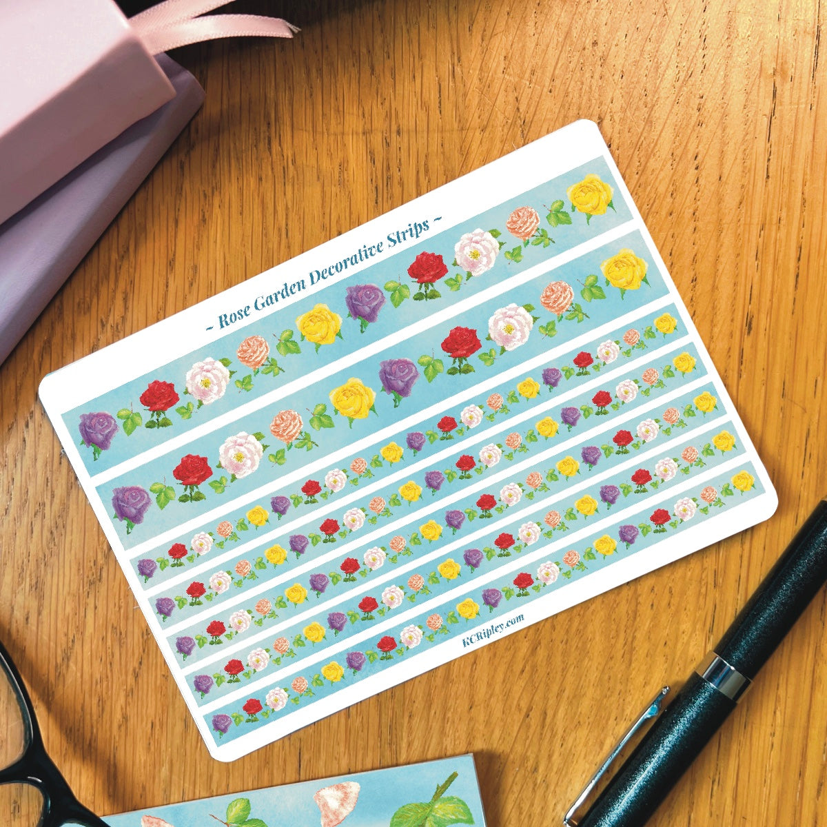 White sticker sheet with 2 wide and 2 narrow sticker strips. Strips are light blue with a repeating pattern of colourful roses