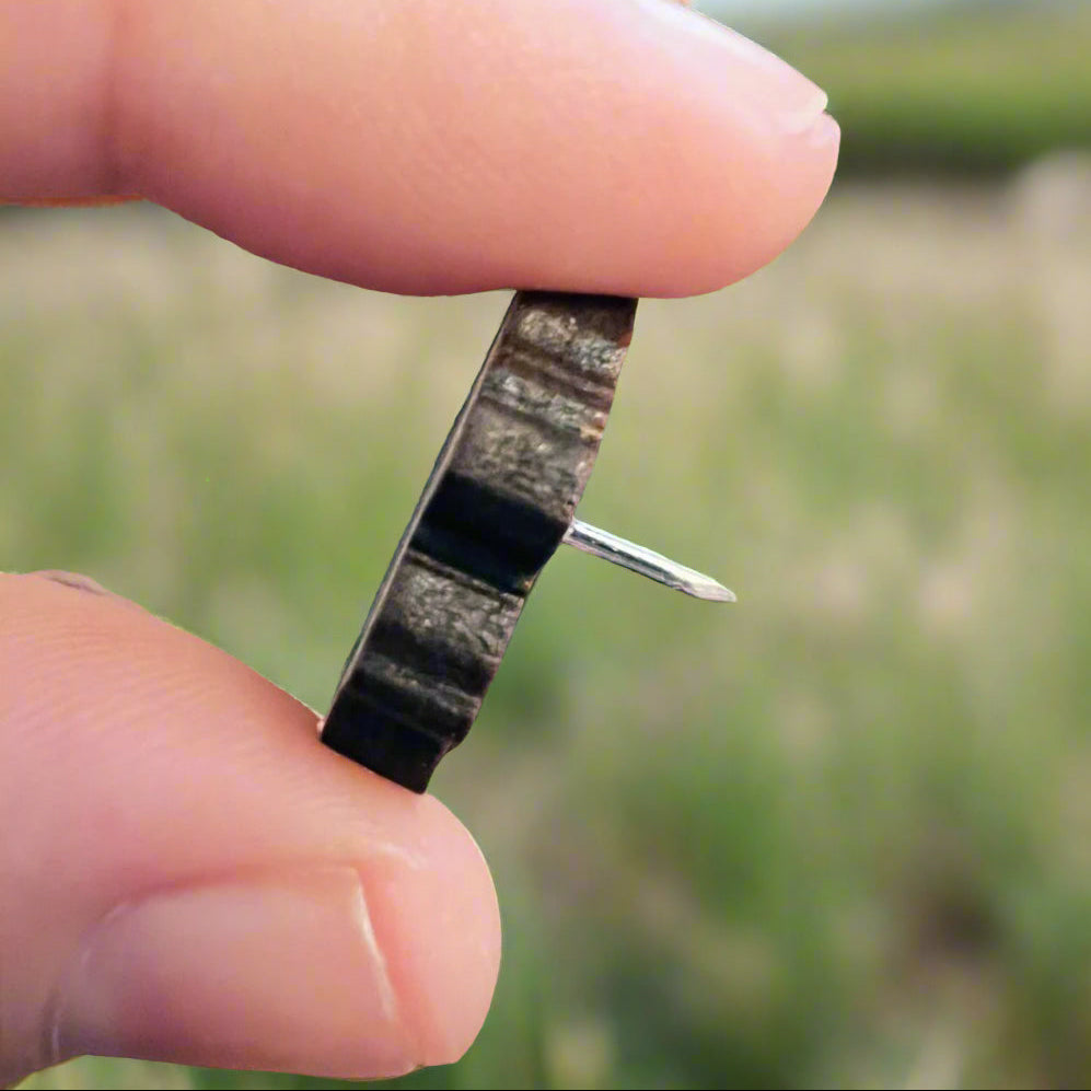 Close up side view of wooden pin showing dark edging and a silver pin back