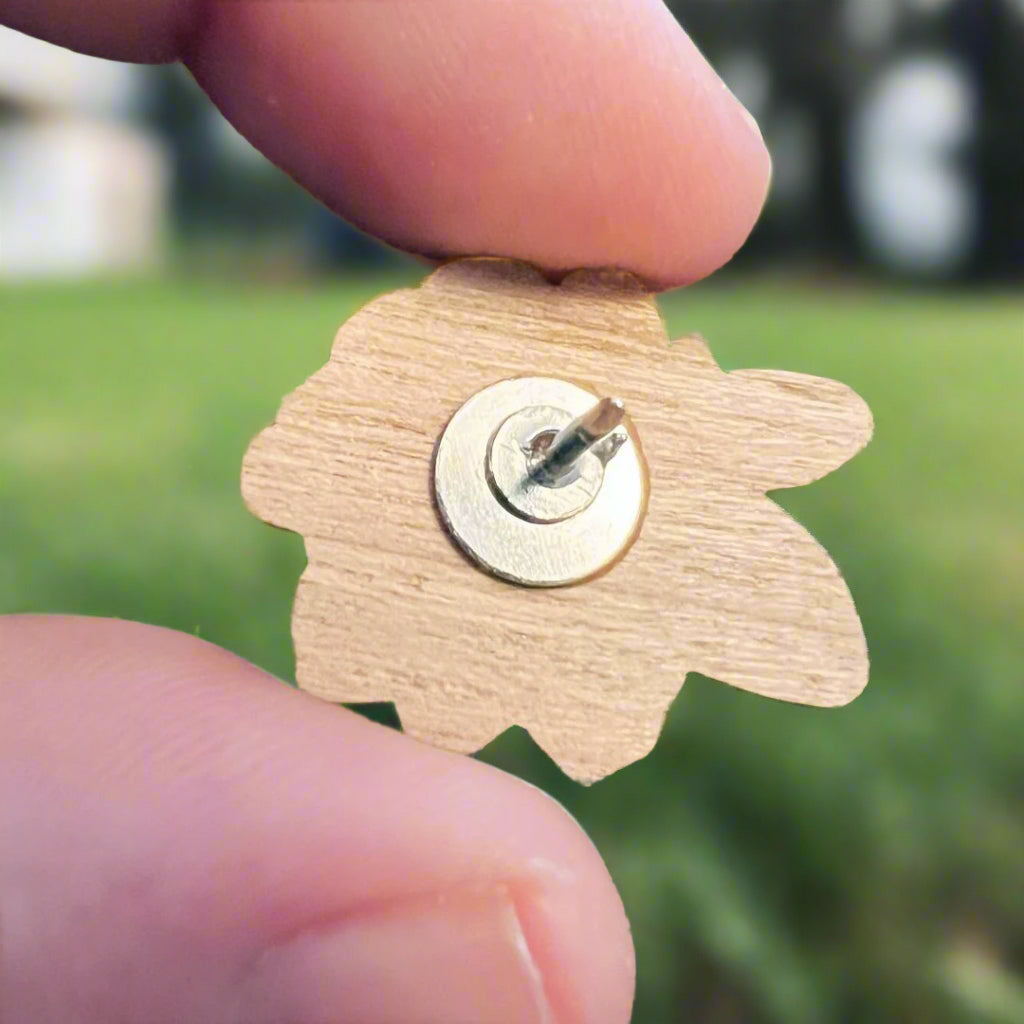 Close up of reverse of wooden pin showing silver pin back