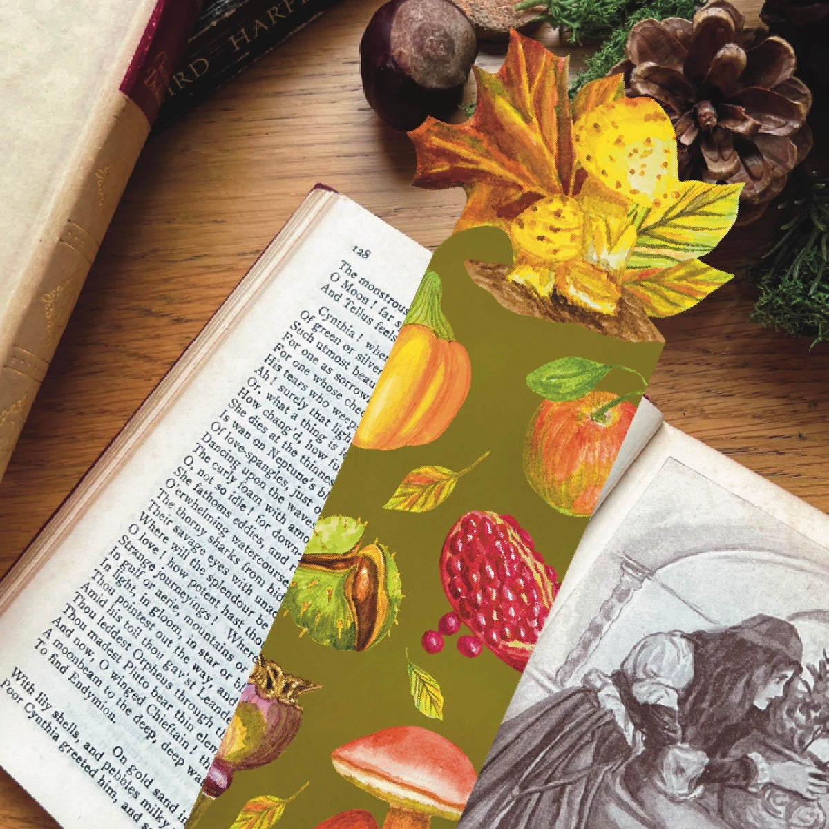 Close up of die cut bookmark in moss green illustrated with harvest fruits and mushrooms, die cut to the shape of maple leaf and mushrooms.  Bookmark lays on the open pages of a book.