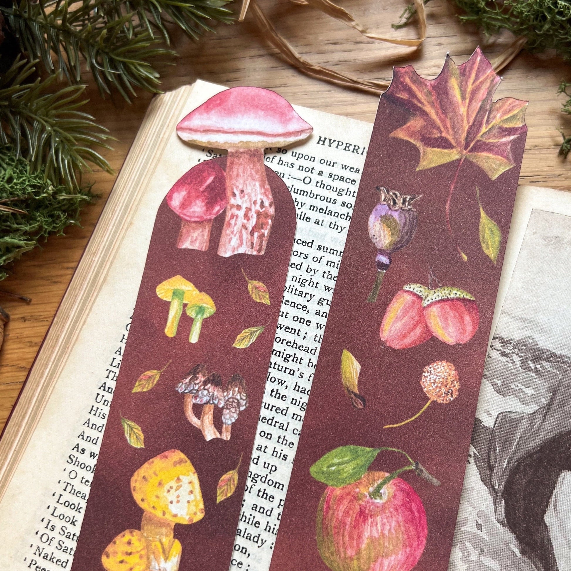 Fall Forage and Woodland Walk bookmarks sat on an open poetry book, resting in a wooden desk decorated with green moss and straw