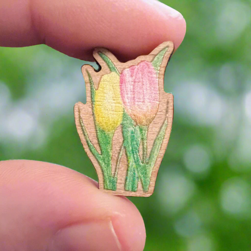 Tulip die cut wooden pin held in front of blurry garden